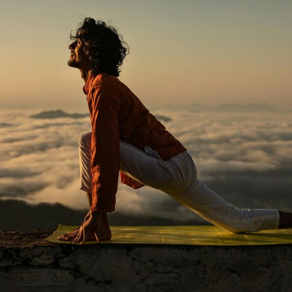 A serene man stretching outdoors at sunrise, feeling refreshed.